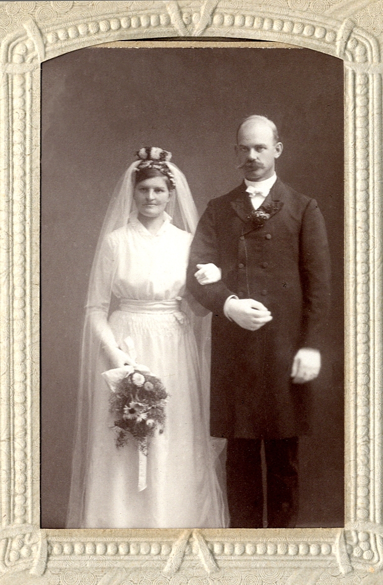 Foto av ett brudpar, 5 oktober 1915. Hon är klädd i vit brudklänning med slöja. Han är klädd i bonjour. 
Knäbild. Ateljéfoto.