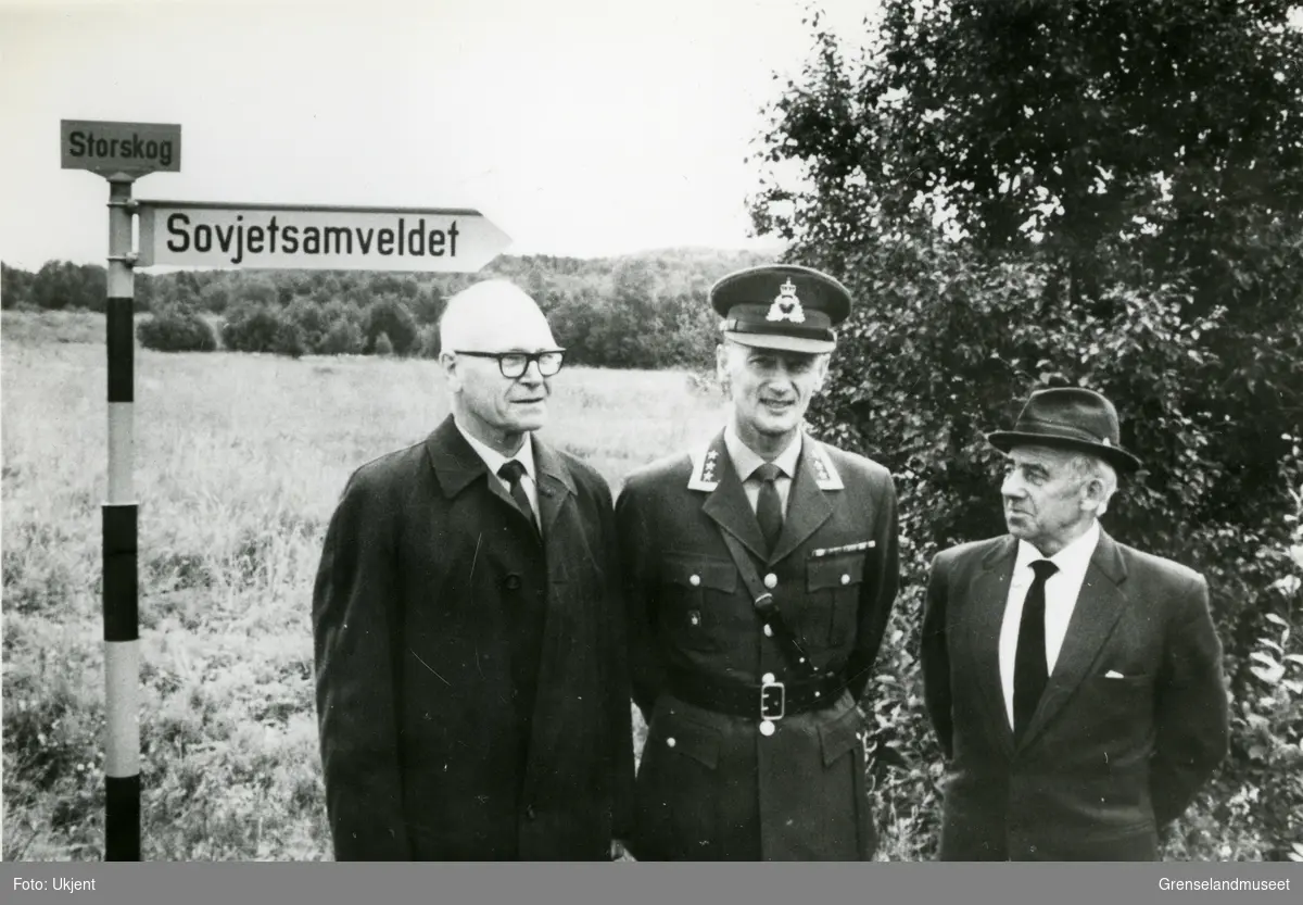 Til venstre står den første norske grensekommisær, oberst Audun Magnus. I midten står oberst Odd Stub Aune, og til høyre sersjant Leif Tharaldsen som i mange år gjorde tjeneste ved konferansehuset på Storskog. Bildet er tatt ved Storskog.