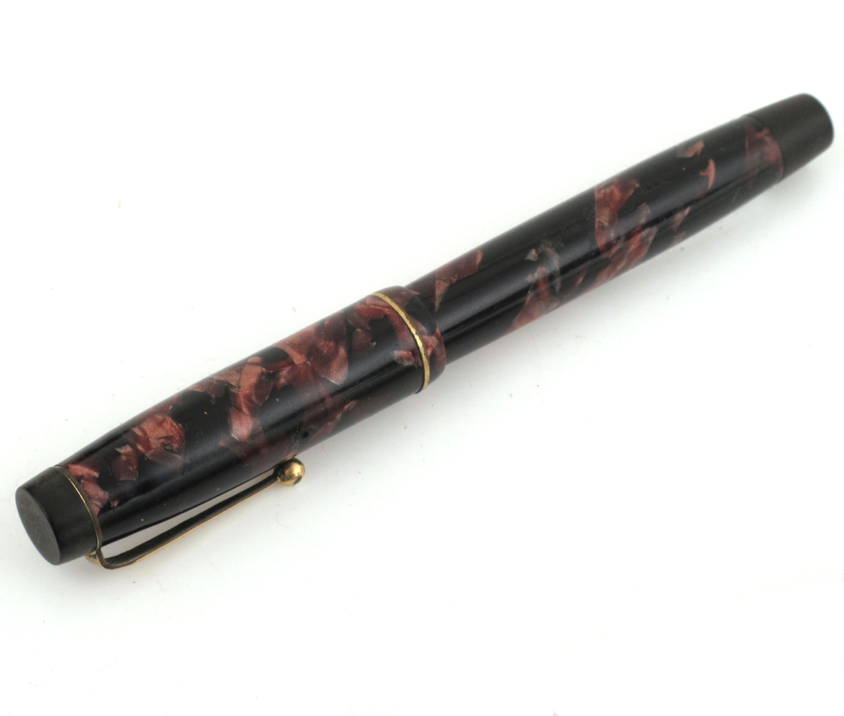 Fyllepenn, sort med mønster i rosavalører.
Pennen inneholder en beholder og blekk suges opp i beholderen fra et blekkhus.
