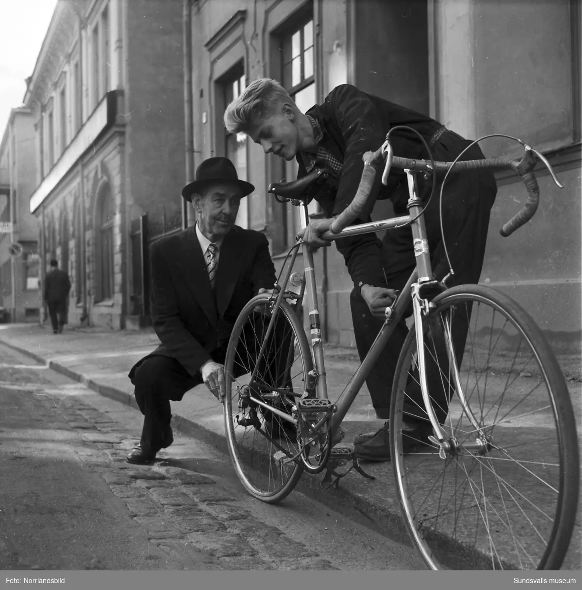 Cykeltränare Tor Östberg och en cyklist inspekterar en tävlingscykel på Rådhusgatan 9.