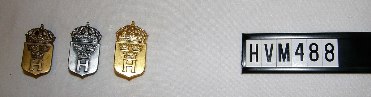 Sköld med kunglig krona. Bokstaven H och tre kronor(symbol)
Brons 3 år(ungdom). Silver 5 år, Guld 8 år(får ej utdelas efter 1951)