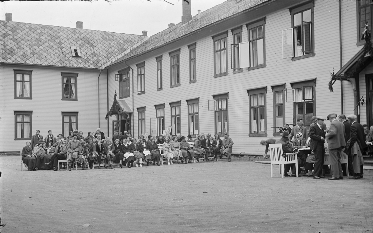 Østre Gausdal, Follebu, Skytekonkurranse utenfor Granheim sanatorium, muligens et skytterstevne. En fane langs veggen og et par personer med flagg.