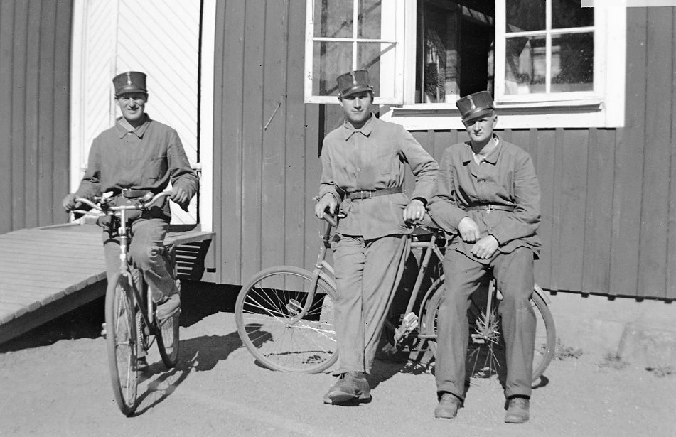 Tre värpliktiga utanför byggnad. Linnekläder. Cyklarna är m/01 som kom att finnas inom krigsmakten fram till 1950-talet.