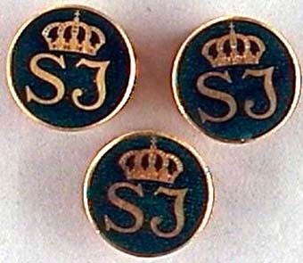 Tre kavajnålar av guldfärgad metall med mörkgrön emaljerad botten. Med krönt SJ-monogram i guld.