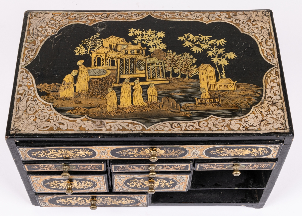 Kat.kort:
Skrin, kinesiskt lackarbete i svart, guld och silver, med landskapsbild och växtornament. Innehåller 9 små lådor, av vilka en är smal, sträckande sig över hela schatullets längd. Några av lådorna äro indelade i fack. Innuti klädda med rödaktig sammet. På undersidan av vänster låda nertill är skrivet "Philip Berhard Hebbe...1772" /el. 1779?/. Gästrikland.