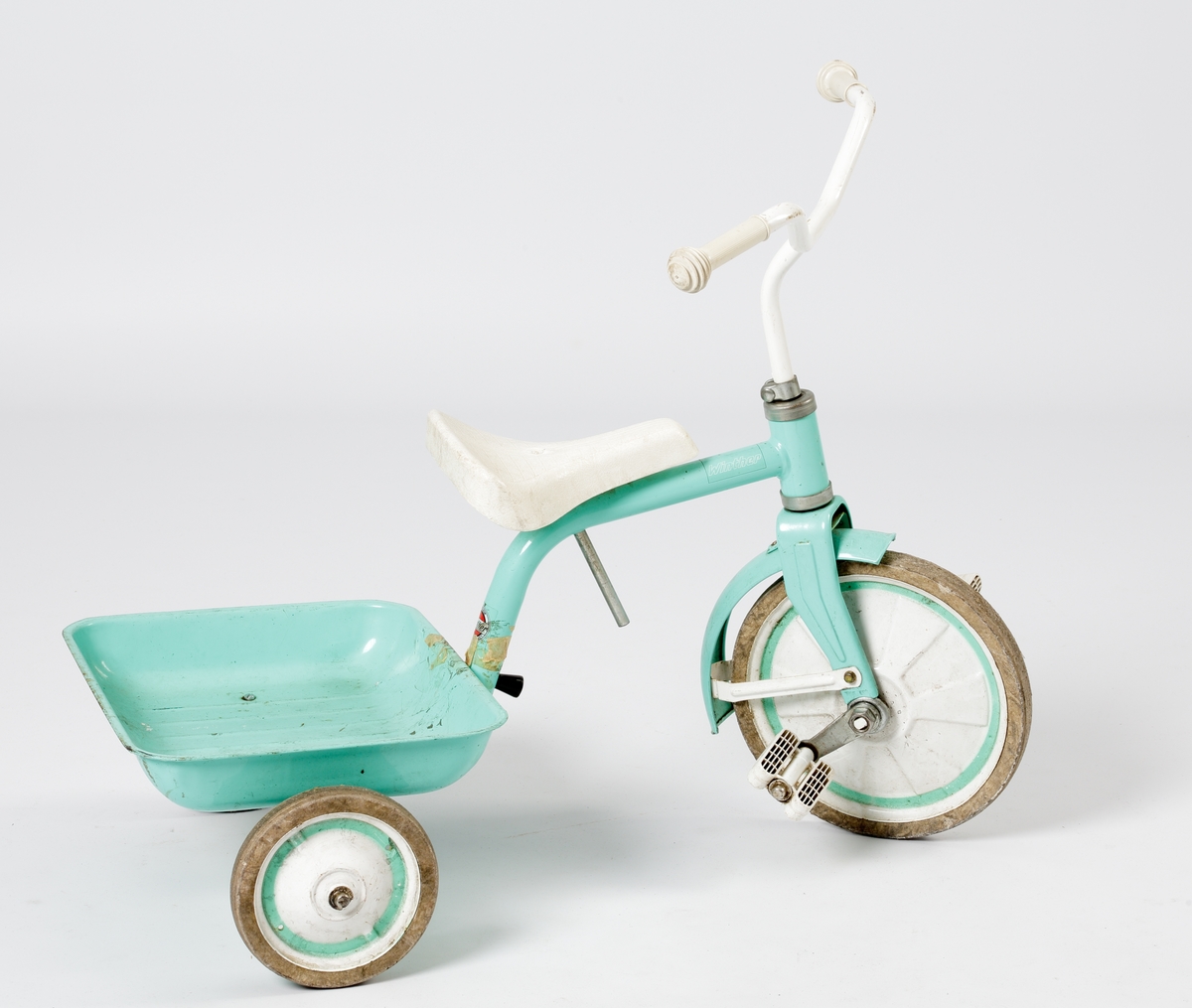 En trehjuling av stål med fällbart flak. Lackerad i mintgrönt med handtag, sits och pedaler m.m. i vit plast.