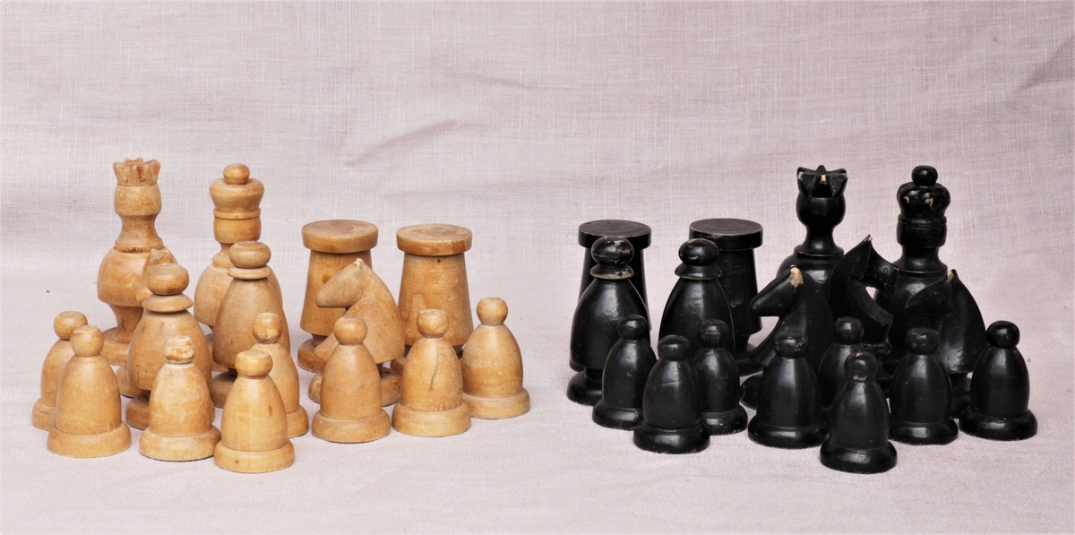 Hjemmelaget sjakkspill. Brettet er malt i hvitt og brunt. Brikkene er sortmalte og trehvite. Spillet er komplett.
