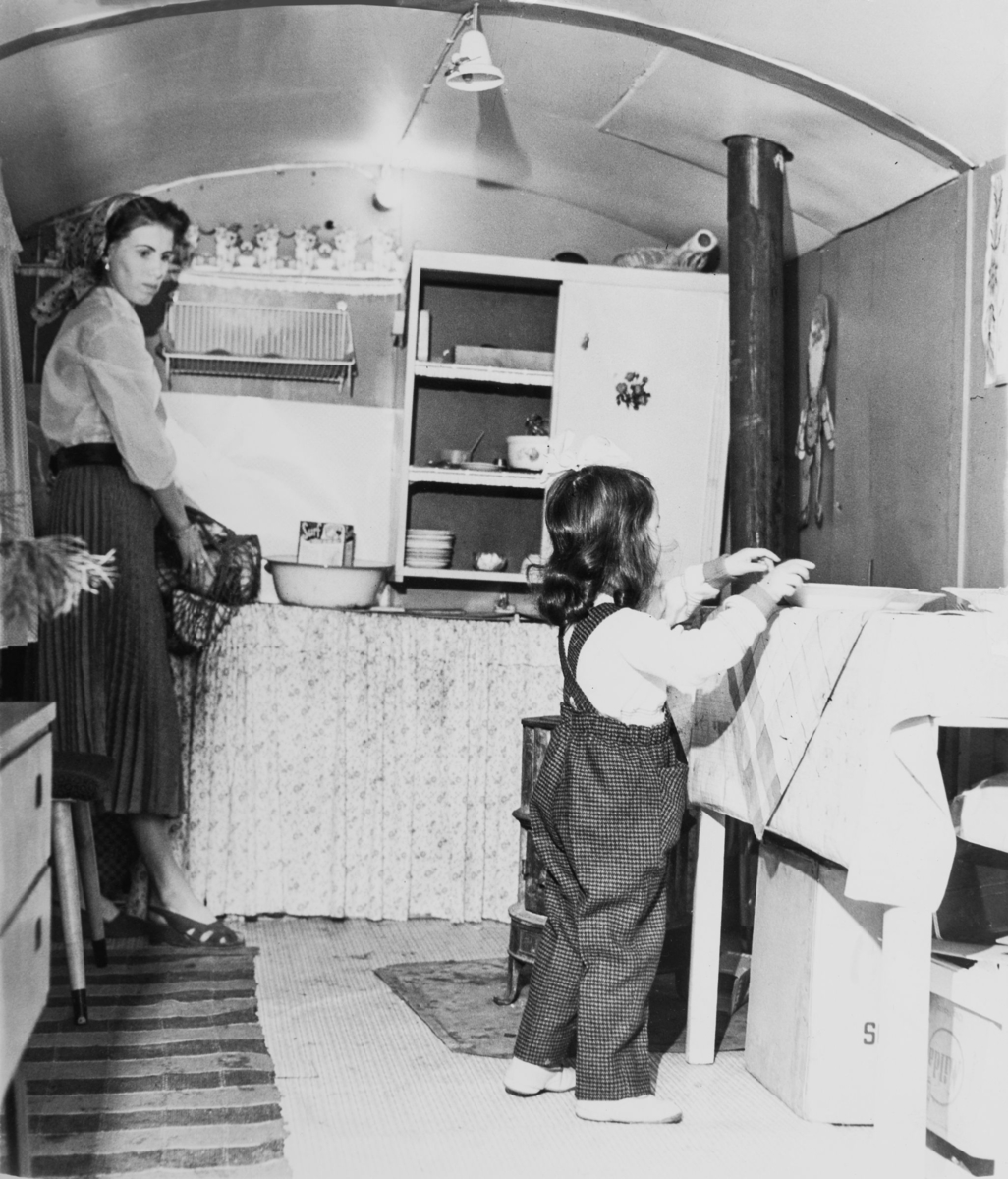 En kvinna och hennes barn står i köket i en romsk vagn.