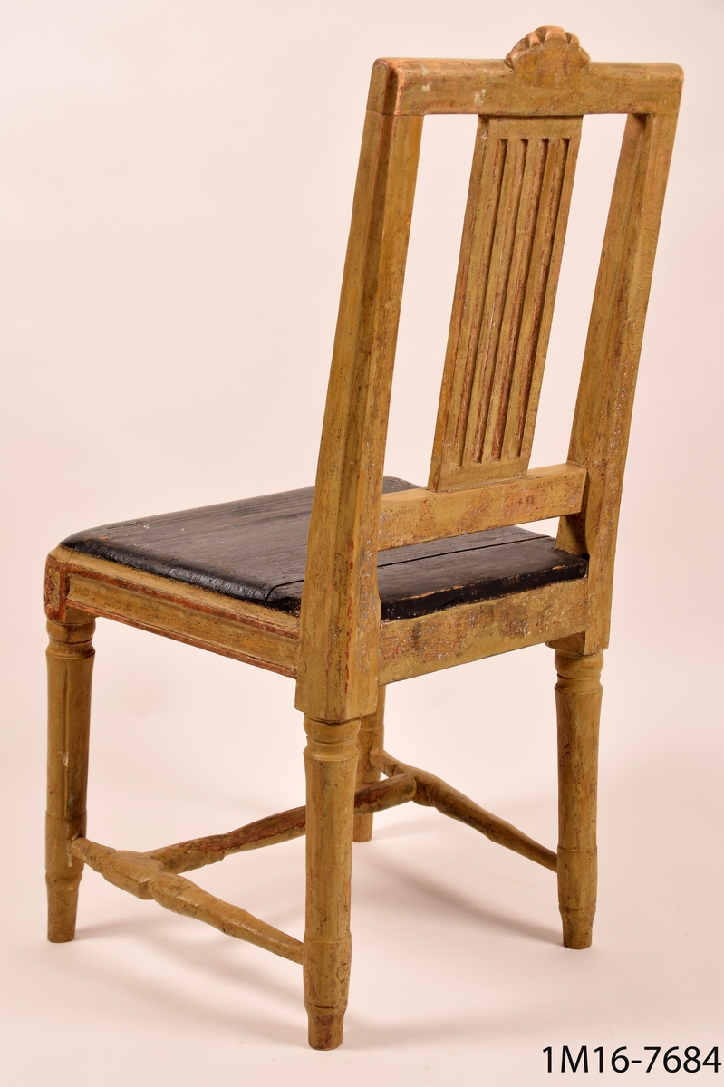 Gråmålad gustaviansk stol med svart sits, svarvade ben med kannelyrer, svarvat benkryss. Genombruten rygg med fyra stycken spjälor, skuret krön med blomma och bladmönster.