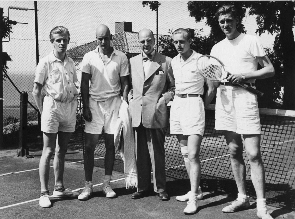 Gränna Tennisklubbs serielag, segrare i Smålandsserien div II 1951. De står på tennisplan utmed Jönköpingsvägen i Gränna. Från vänster: Henry Boberg, Ulf von Otter, lagkapten Osse Gustavsson i kostym, Björn Ander samt Rolf von Otter.