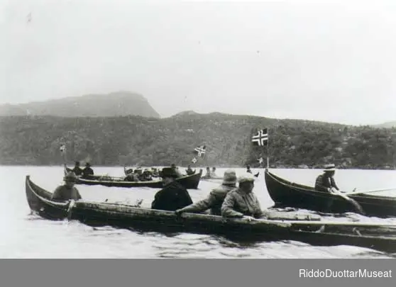 Elvebåter med flagg på vei mot Skoganvarre. Stortingets samferdselskomité på befaring, 1923.