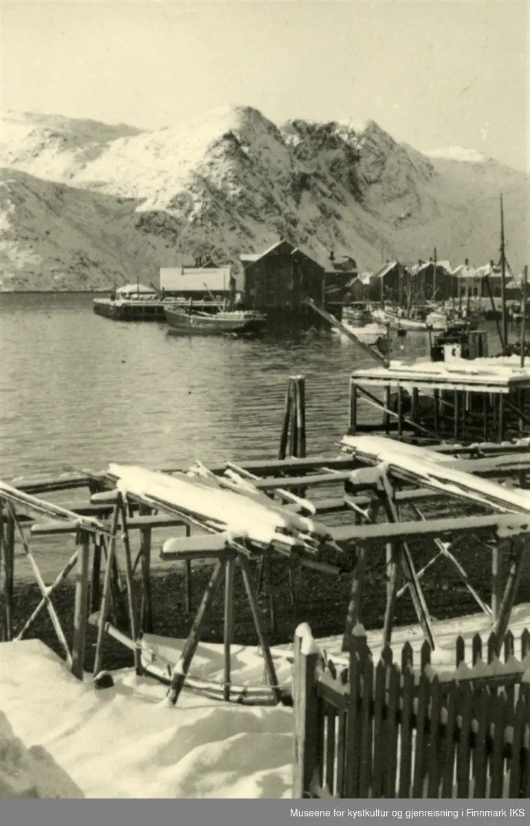 Honningsvåg. Bildet tatt fra Vågen. Dampskipskaia med bebyggelse i bakgrunnen. Fiskehjeller i forgrunnen. 1942.
