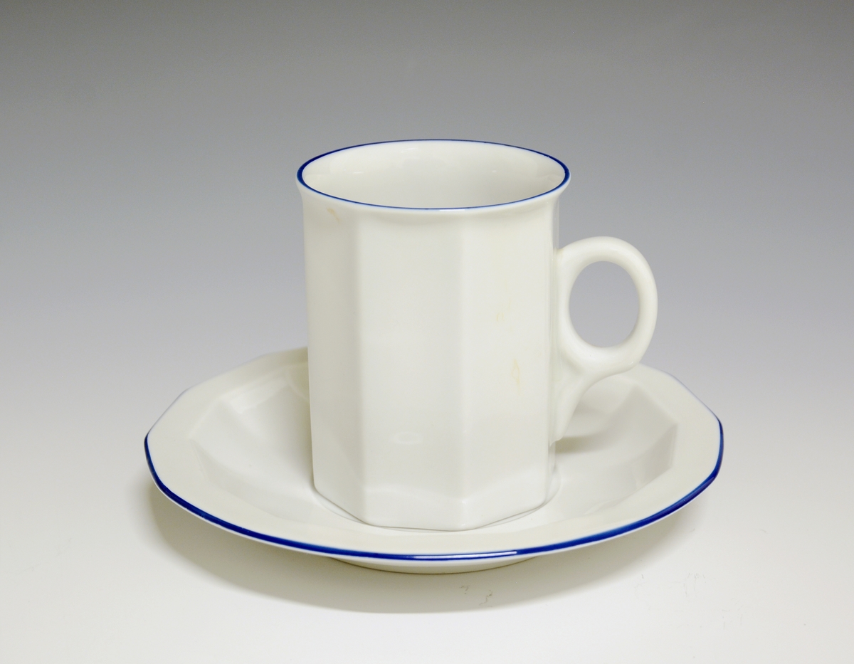 Kaffekopp av porselen. 14-kantet skål med blå strekdekor langs fanens kant.
Modell: Octavia, tegnet av Grete Rønning i 1977
Dekor: Blå strek