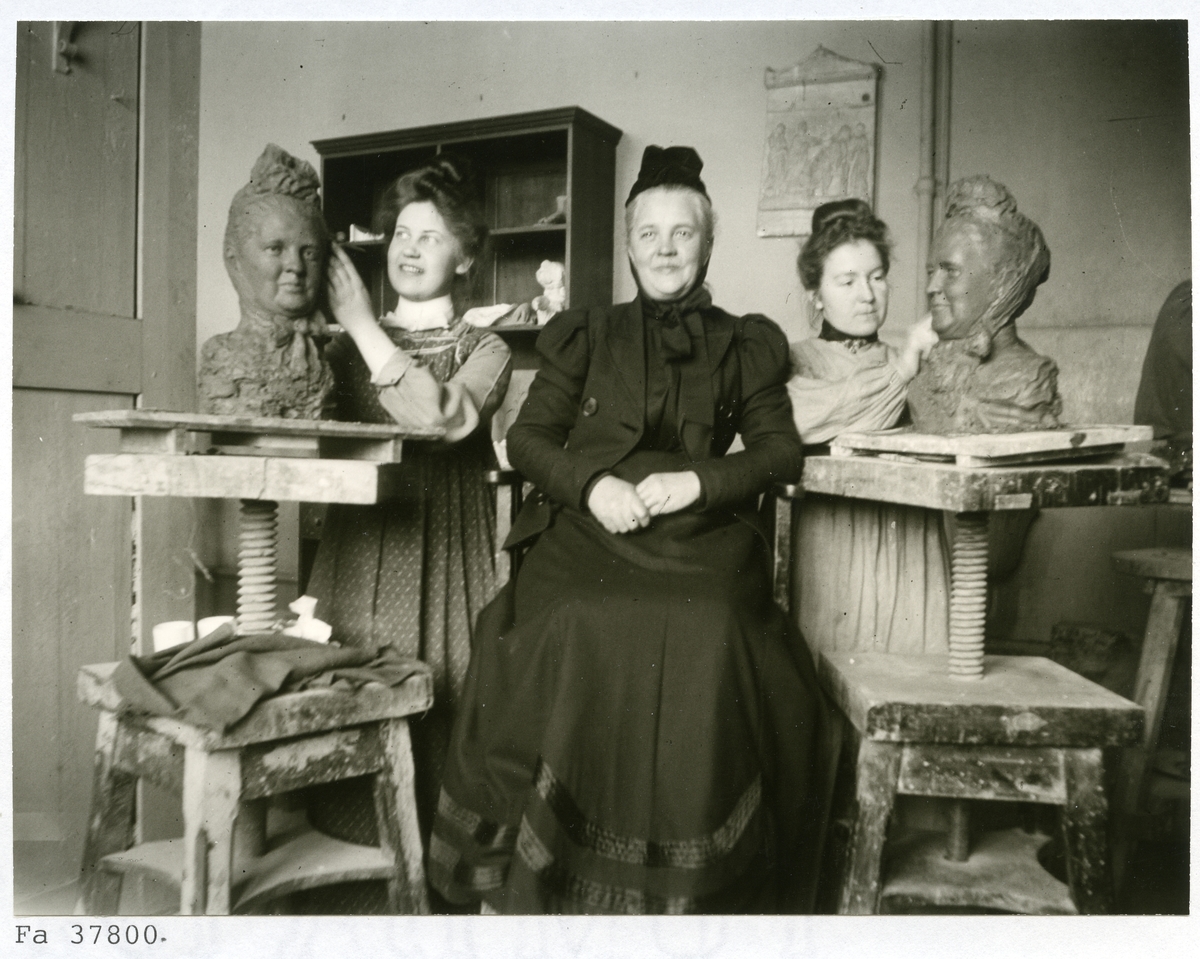 Stockholm. 
Två kvinnor skulpterar av äldre kvinna med liten hatt. 1901.