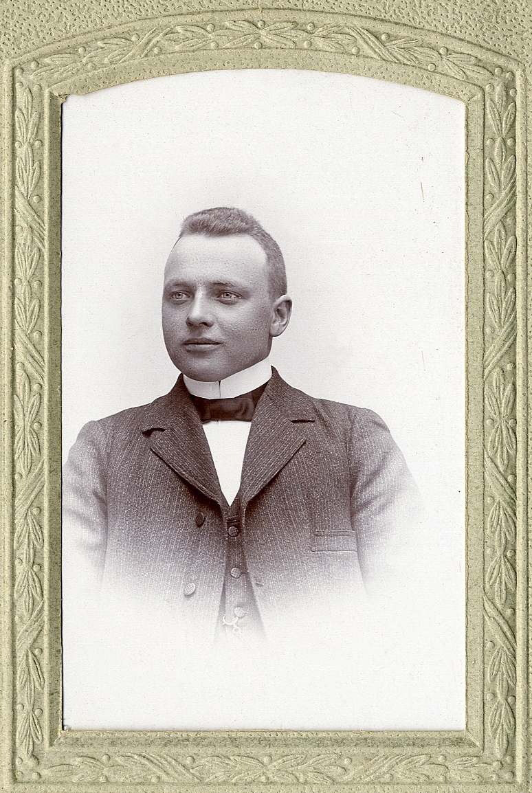 En okänd ung man i kavajkostym av tweed med väst, stärkkrage och fluga. I nedre vänstra hörnet syns ett inpräglat årtal: "1905". 
Bröstbild, halvprofil. Ateljéfoto.