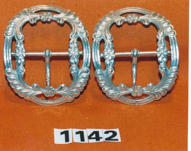 Skospenne i sylv, ovalt med ornament rundt kanten, Torn i midten, stempla under.