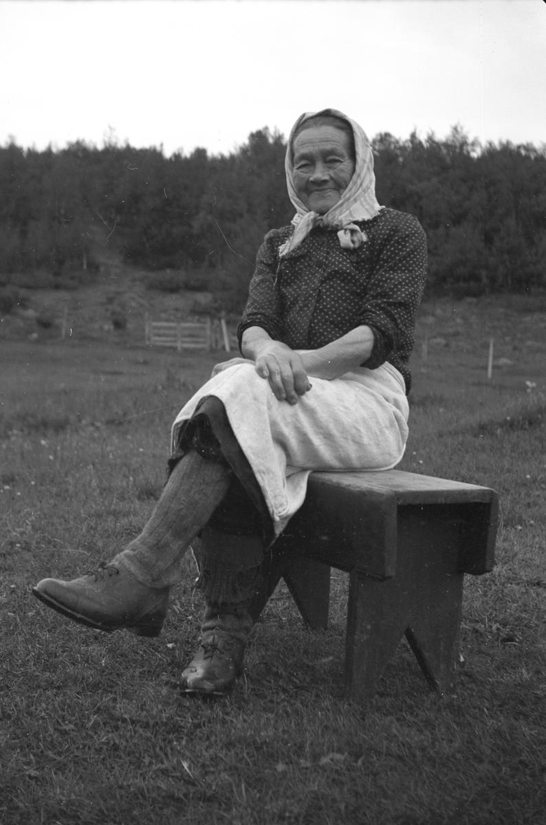 Oline Storbækken, Østerdalens eldste budeie, sitter på en benk kledd i typiske seterklær