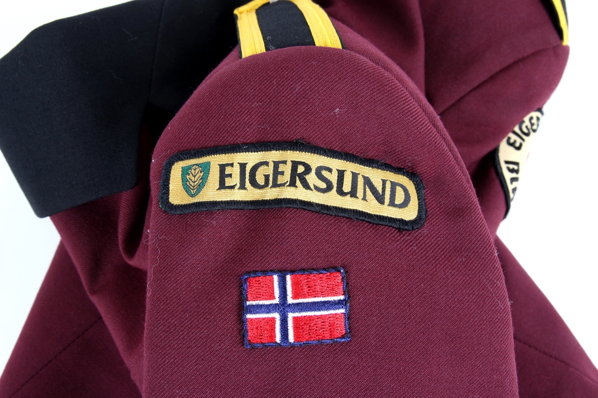 Del av en korpsuniform fra Egersund Brass.

Jakken har messingknapper, samt påsydde tøymerker og flagg.