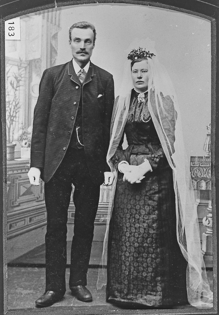 Brudebilde av Steinar Jakobsen Skare og Kari Torstensd (f. Mykstu). Han i dress, hun i svart kjole med langt, hvitt slør. Atelier-foto, rundt århundreskiftet.