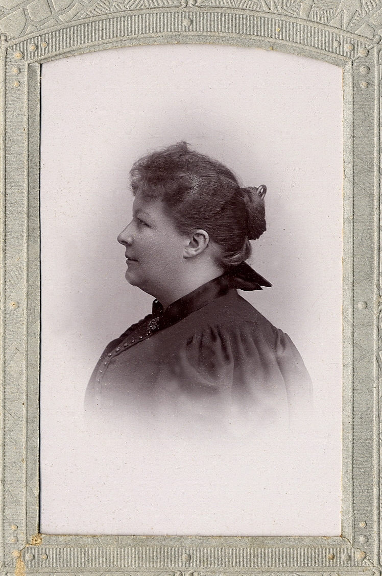 En okänd kvinna i mörk klänning med hög krage. Vid kragen skymtar en brosch. 
Bröstbild, profil. Ateljéfoto.

Kan ev. vara fotografens syster, fru Johanna Bergman, f. Larsson (1861-1935), Ljungby.