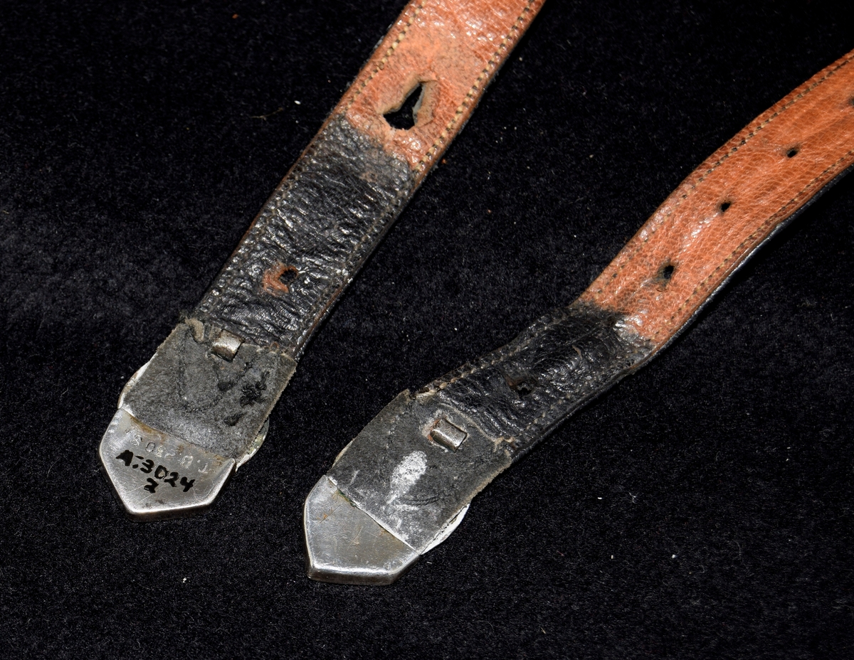 "Sprett og sprota" til å holde strømpene oppe. Lærremmer med sølvspenner og sølvtupper i endene. Den ene spennen er en kopi laget i tynnere materiale.