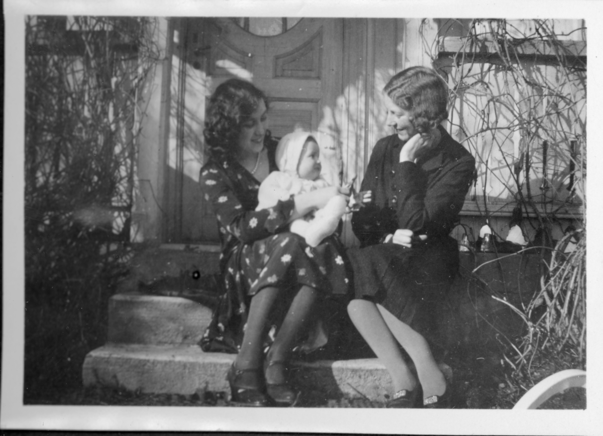 Kvinne med baby på fang og venninne, sittende i trapp. 1930-tall.