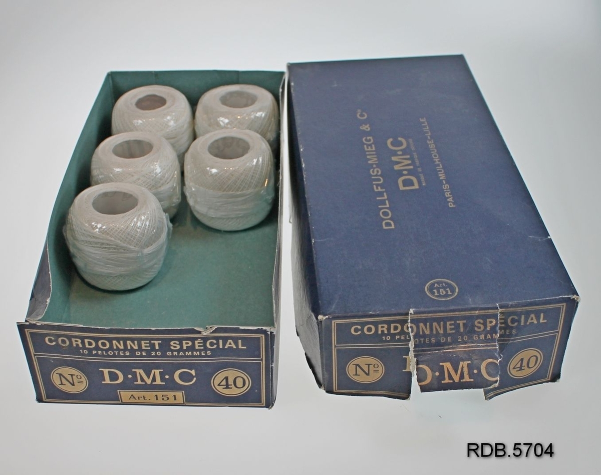 En blå pappeske som inneholder 5 nøster DMC bleket hvitt bomullsbrodergarn nr 40. Eska er opprevet i fronten.
