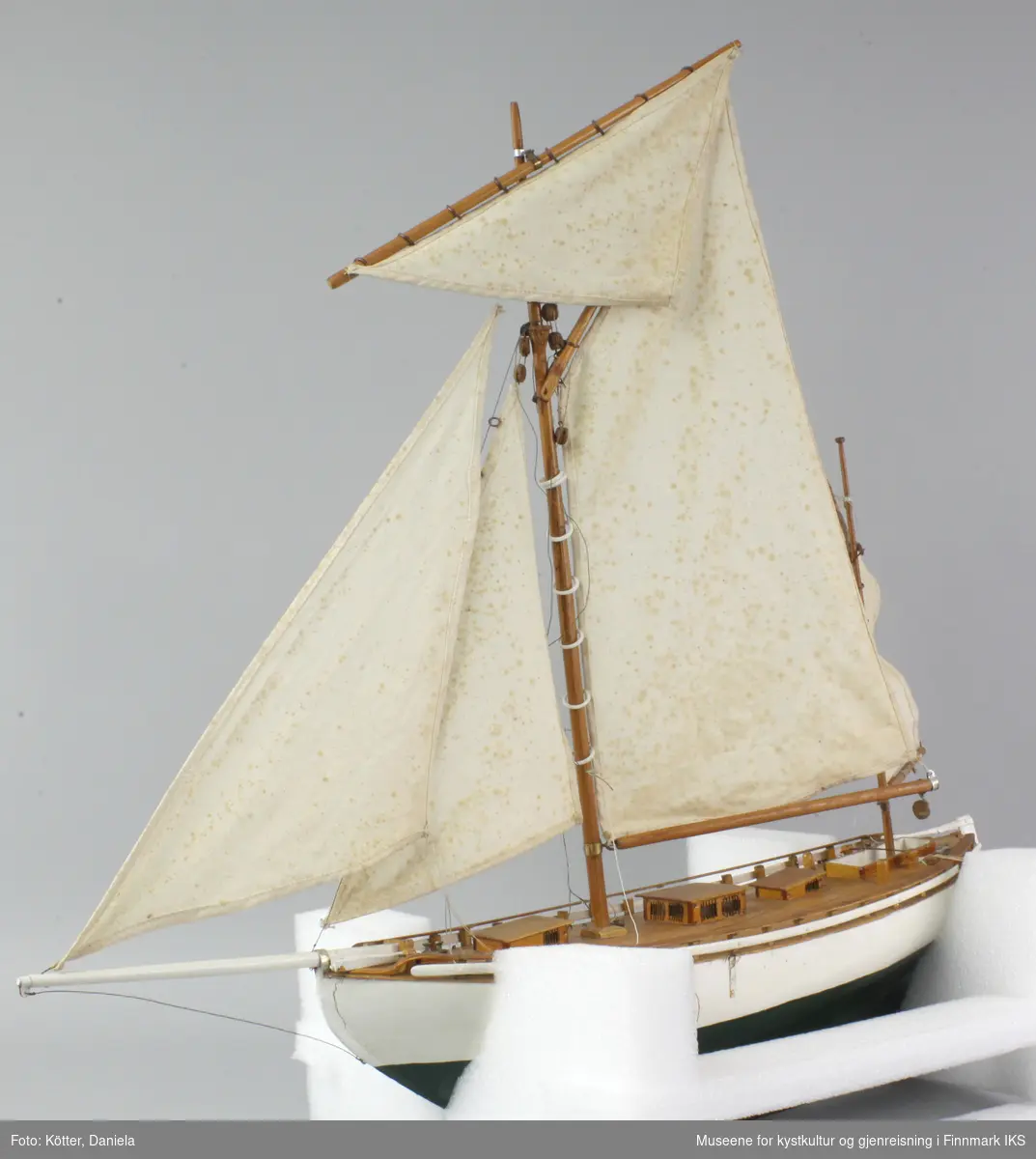Modellbåten er hvit med grønn kjøl. Seilskøyten er spiss i begge endene og er gaffelrigget med fem seil. Den er en del løse deler.