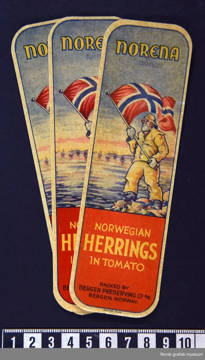 Etiketter med en fremstilling av en skjegget mann med gult oljehyre (regntøy) som holder oppe det norske flagget. 

"Norwegian herring in tomato"