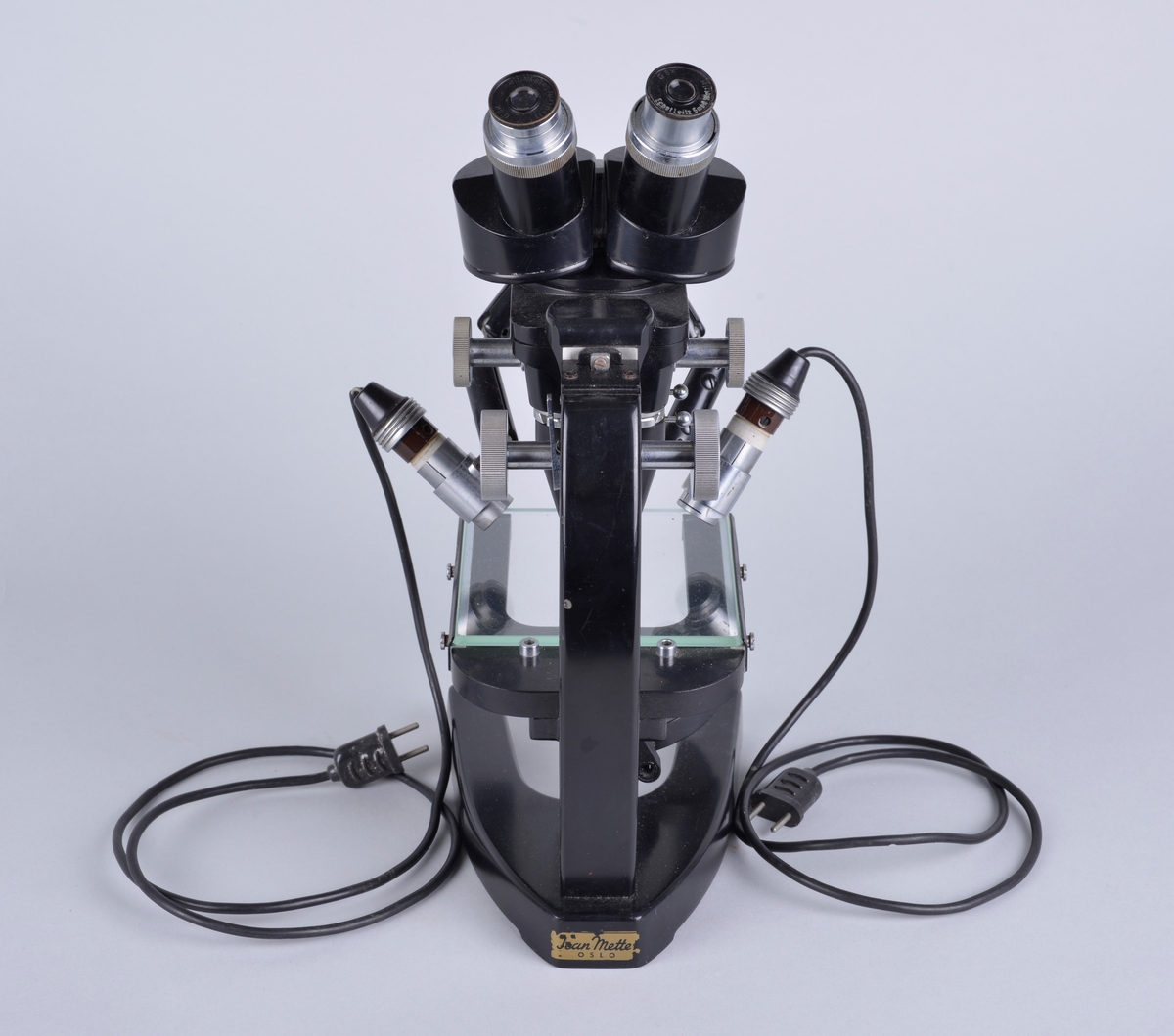 Binokulært mikroskop, har to okularer for bruk med begge øyne.
Apparatet er produsert i Tyskeland og brukt av Vetrinærinstituttets fagfolk. 

Chassiet er muligens laget i stål, svartlakkert.