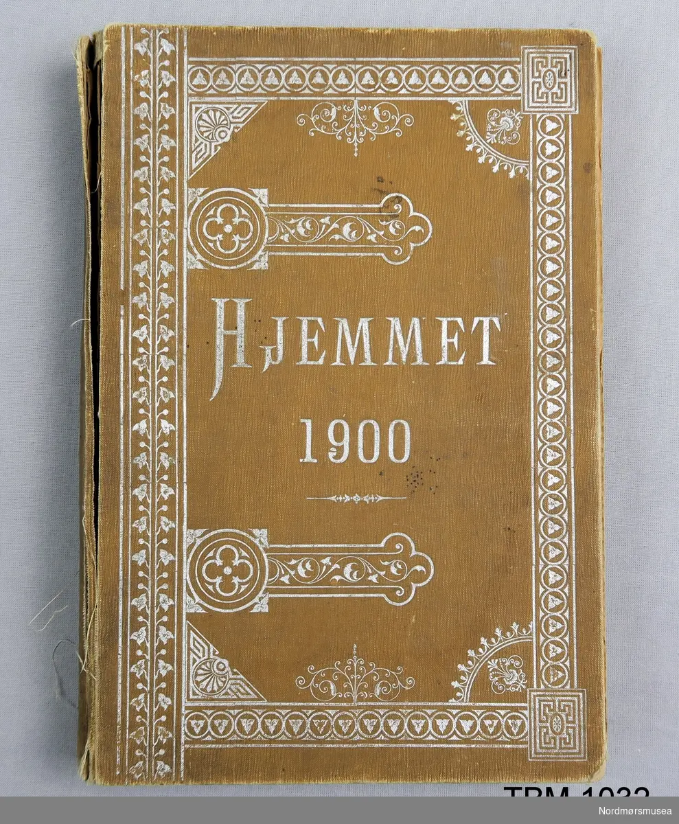Pent innbunden bok med årgang 1900 av bladet Hjemmet,
Brune, stive permar med djuptrykte bordar i bleika gull.
Gotisk skrift.