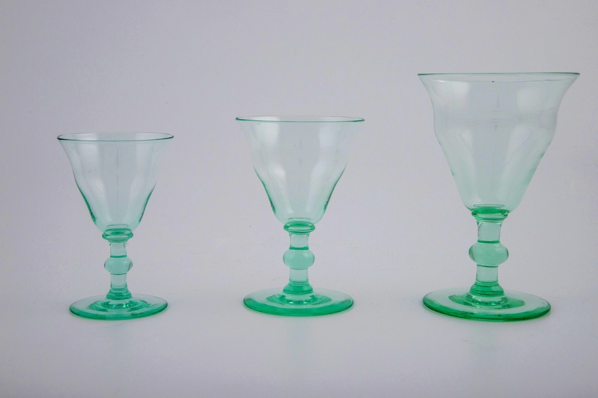 Tre vinglass av gjennomskinnelig glass med grønnlig tone. Buktende klokkeformet kupa, stett med vulst, svakt skrånende fotplate. Glassene er i tre ulike høyder.