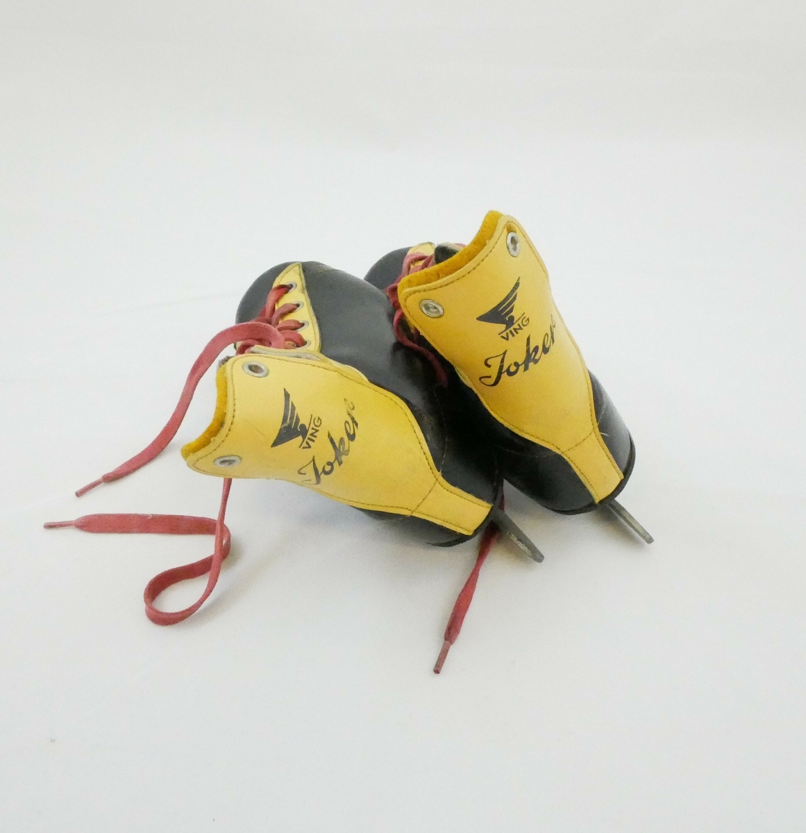 Skøyter med påfestede sko i sort og gult med røde lisser. Hvit såle på innsiden. 
