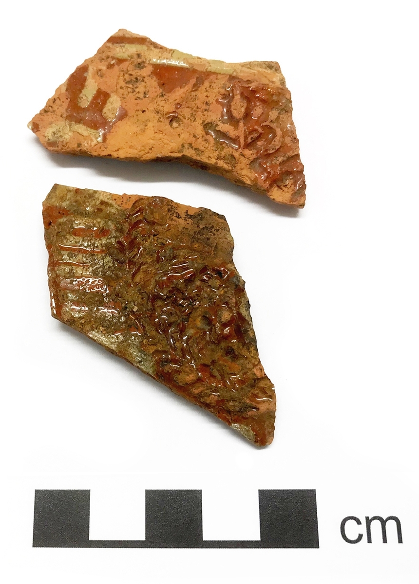 Relieffdekor med krans, röd och grön glasyr och vitlerränder. Troligen tysk import tillverkad i slutet av 1500-talet.
5 fragment
Kontext: A36