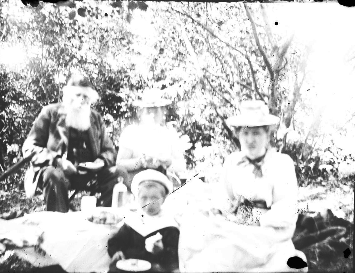 Överexponerad bild med två kvinnor, ett barn och en äldre man som möjligen har picknick i det gröna.