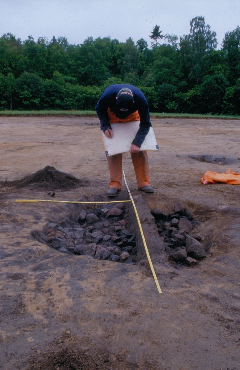 En arkeolog står och dokumenterar en härd. Foto taget vid en arkeologisk undersökning vid Eurostop i Jönköping 1998.