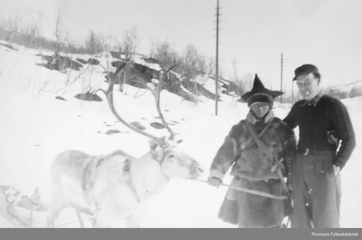 Ivar Iversen (til høyre) og en samisk mann med stjernelua og pesk av reinskinn på. Reinsdyr og en kjelke/pulk står ved siden. Stedet er i Tana rundt 1945-1955? Ivar Iversen bodde senere i Vadsø i Havnegata.