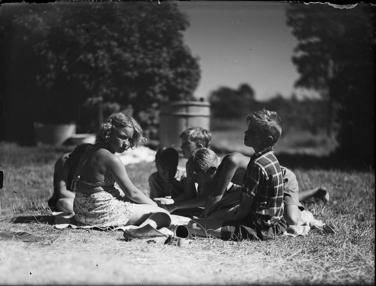 Barnkoloni - barn sitter på en filt i gräset, Sandika, Harg socken, Uppland