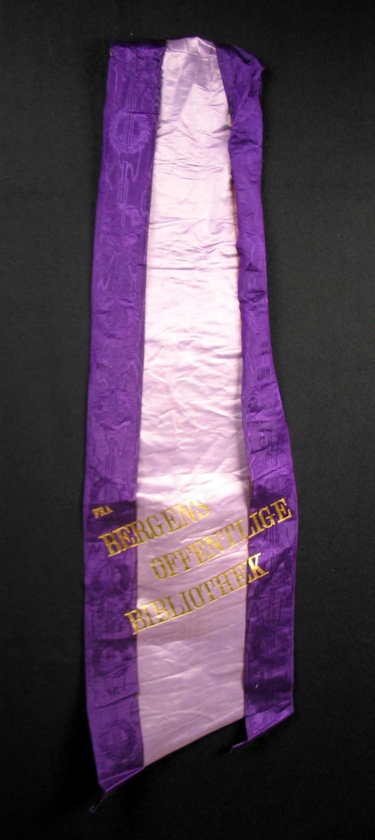 Begravelsessløyfe i lilla silke med skrift i gull.