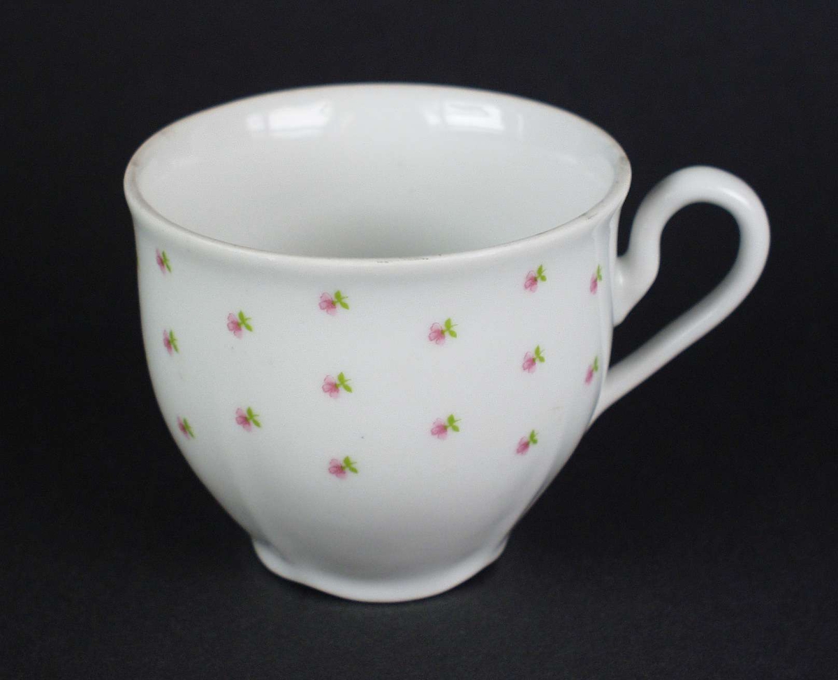 Seks hvite kopper i porselen dekorert med små roser.