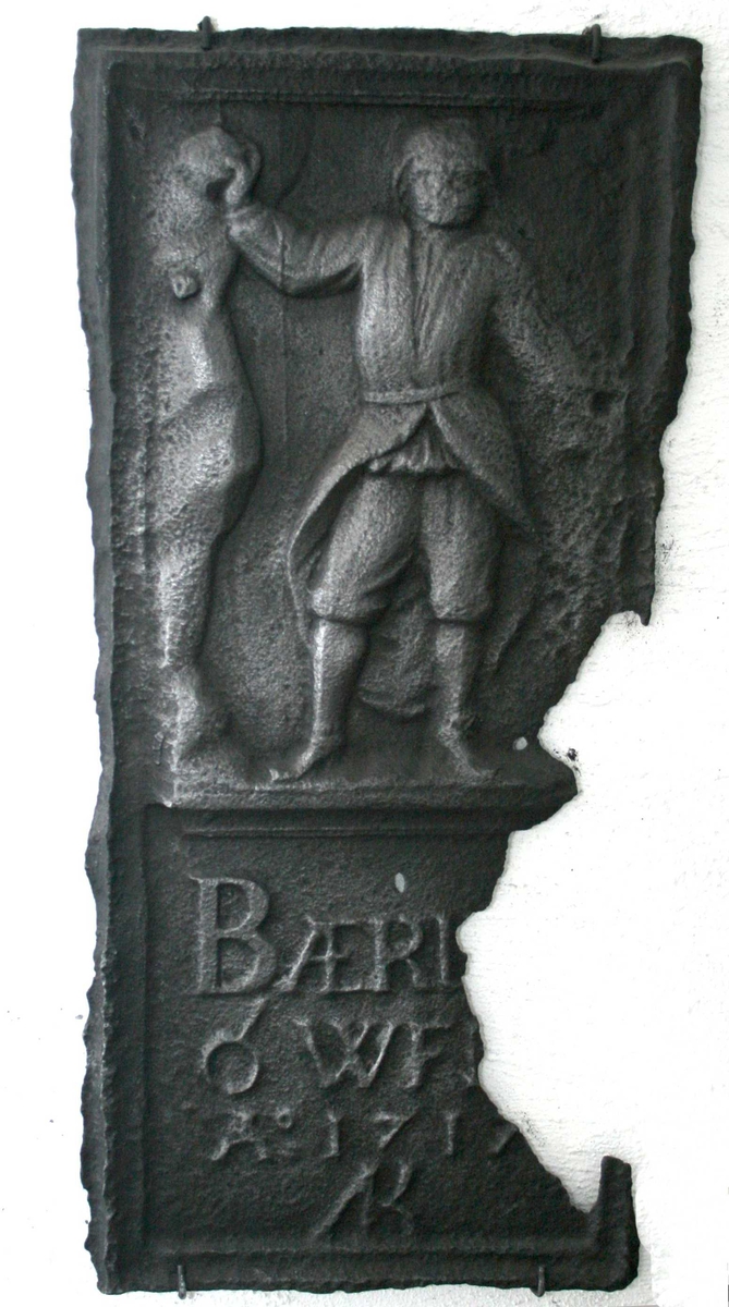 Stiger, (oppsynsmann v. gruvene) med arslær, bergkalott og bergmannsstav (hakkel), i hånden en malmklump. 