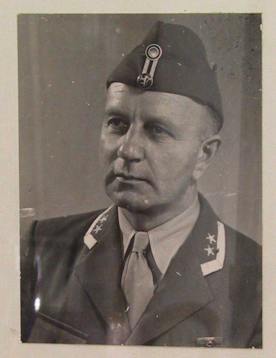 Portrett av  Harald Juell i oberstuniform, ca. 1947.  Brystbilde, halvt venstrevendt,  hodet litt bøyd mot høyre  Alliert uniform med lue. Anta. tatt i Tyskland. hvor Juell var oberst i  de allierte okkuasjonsstyrker etter krigen. 