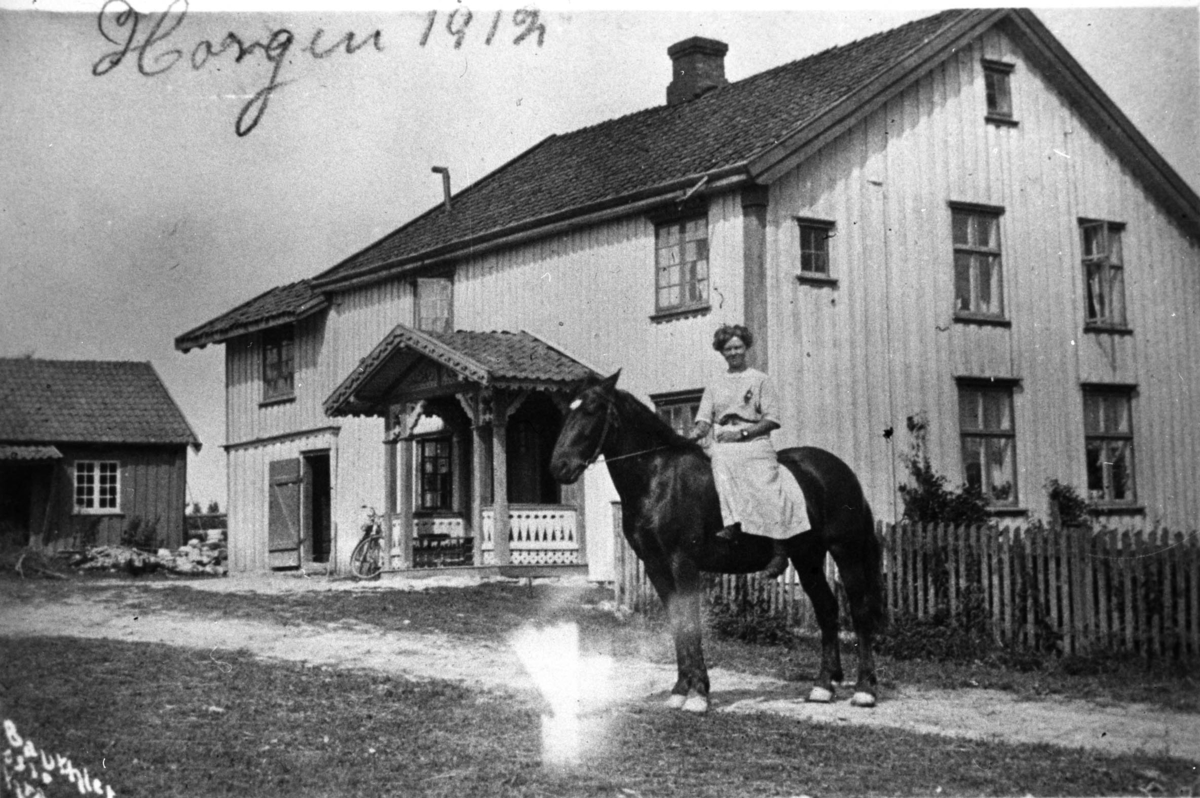 Kvinnelig rytter til hest, bolighus, uthus