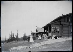 En gruppe mennesker i "bunad" og penklær utenfor et laftet t