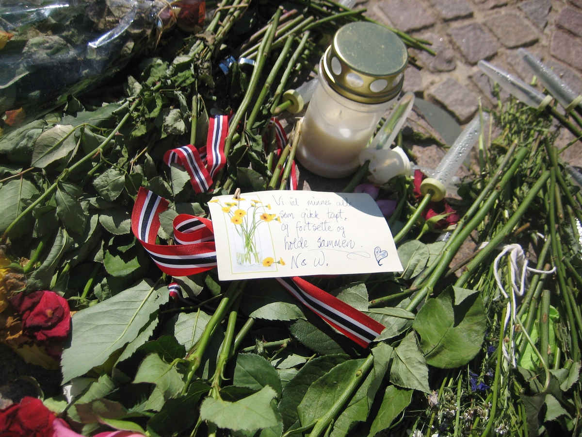 Minner etter terrorhandlingen den 22. juli 2011. Blomster, kort og lykte på fontene på Lillestrøm torg.