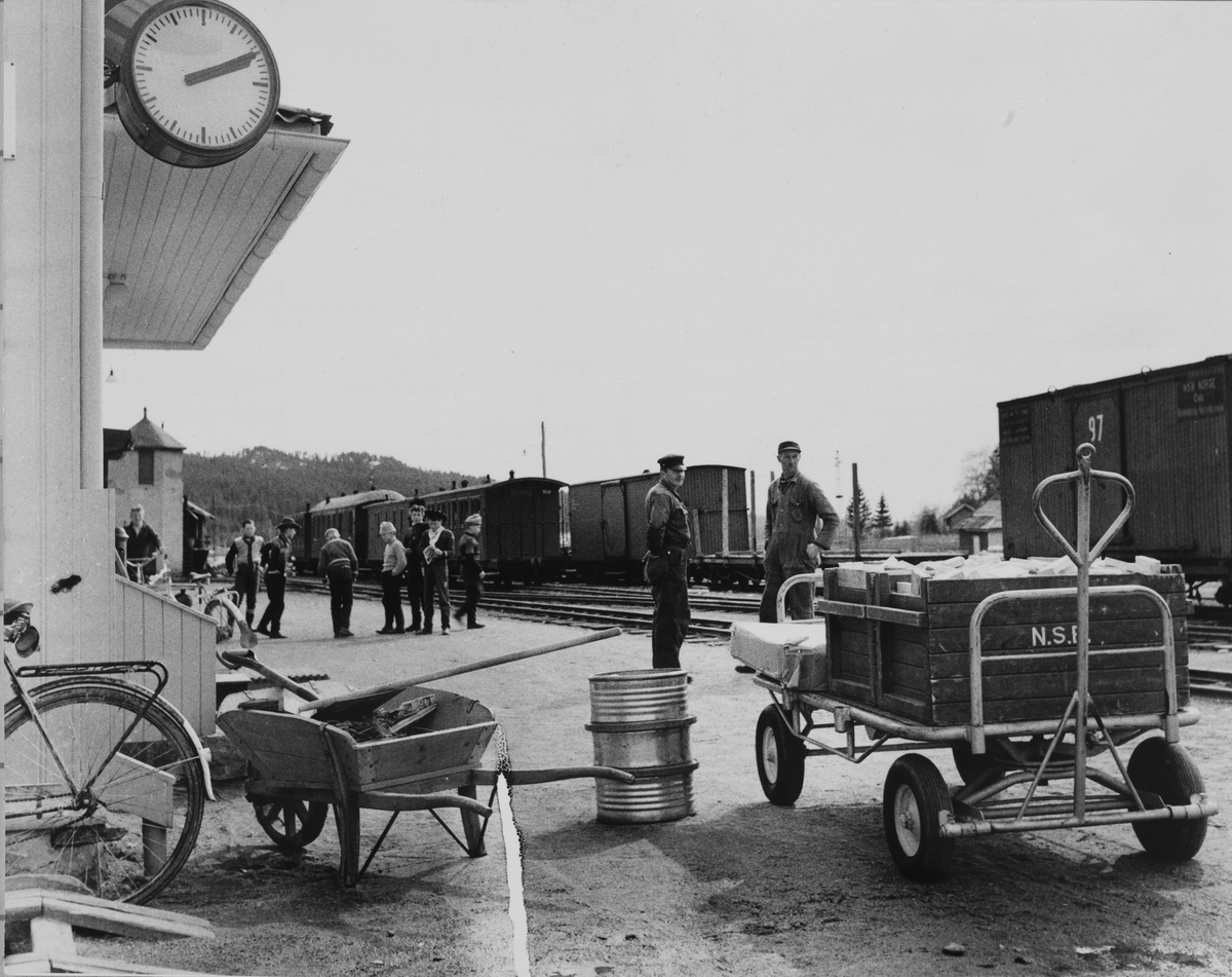 Reisende, gods og jernbaneansatte venter på toget på Bjørkelangen stasjon.