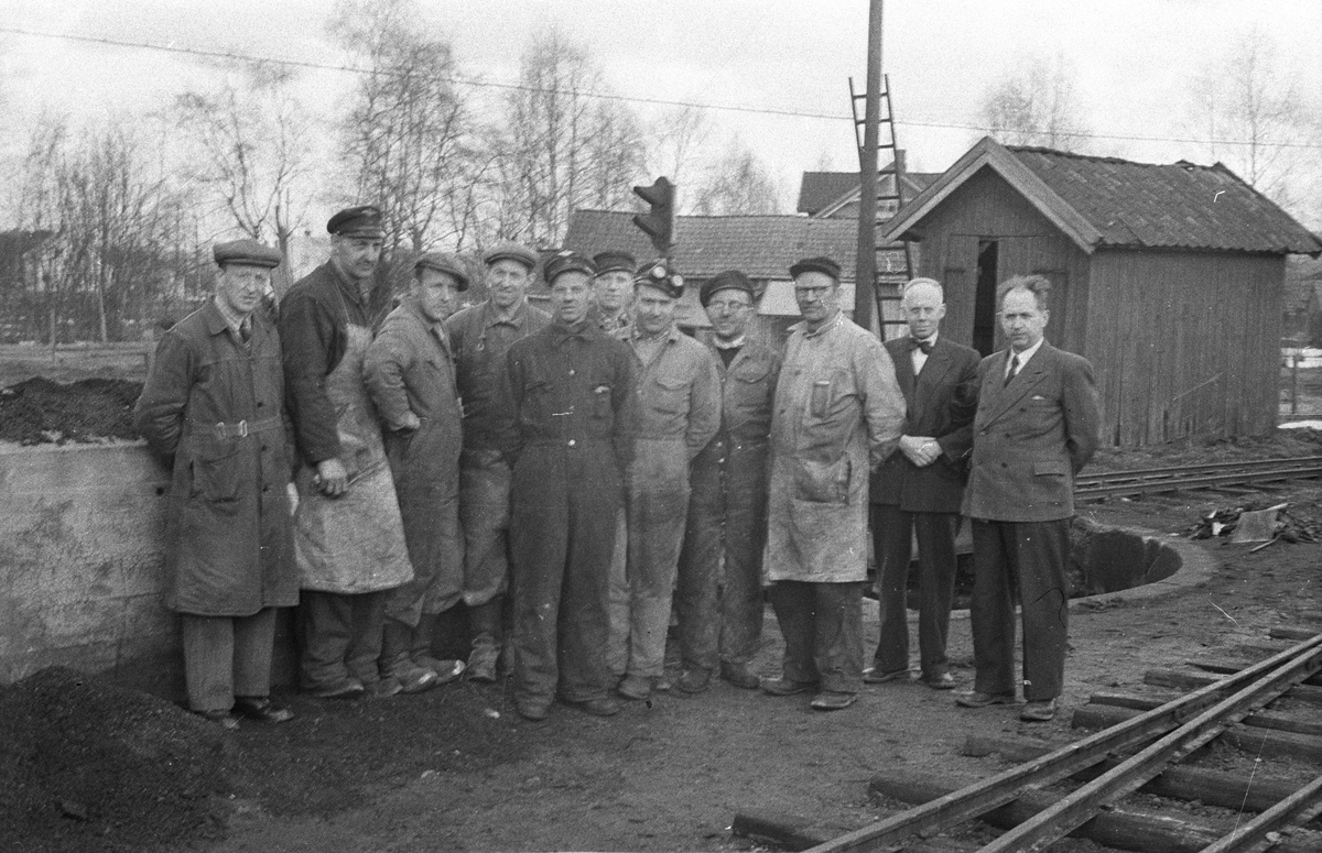 Verkstedpersonale ved Aurskog-Hølandbanen og besøkende ingeniører fra NSB i Oslo utenfor lokomotivstallen på Bjørkelangen
