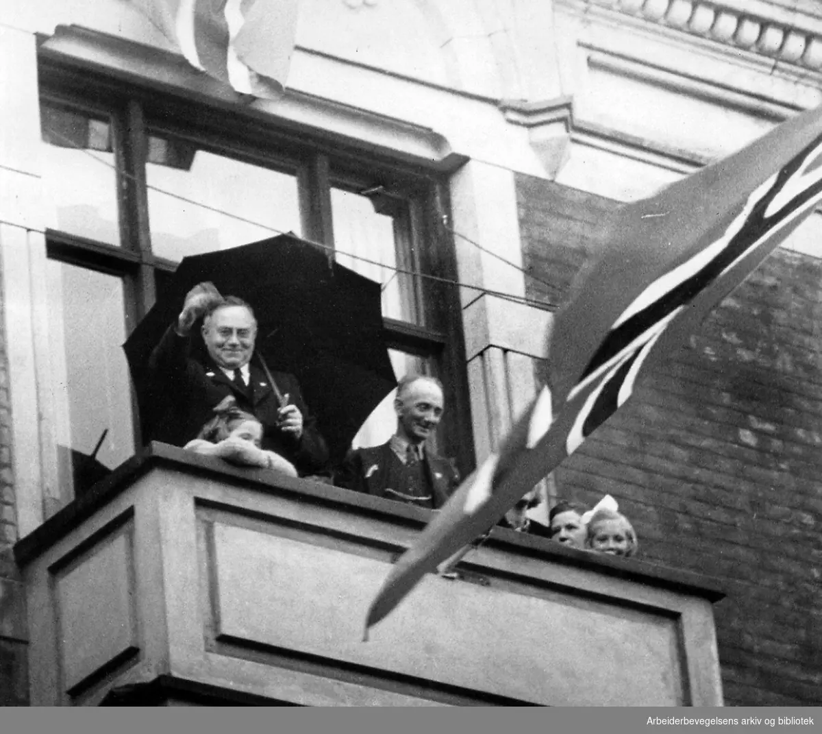 Statsminister Johan Nygaardsvold vinker til folketoget fra balkongen i statsministerboligen i St. Olavs gt. 35,.7. juni 1945