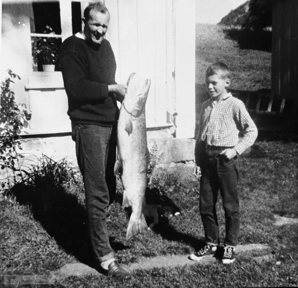 Asbjørn Olav Øveraas med en laks på 13 kg. tatt i Eikesdals - vatnet. Aslak ser på.