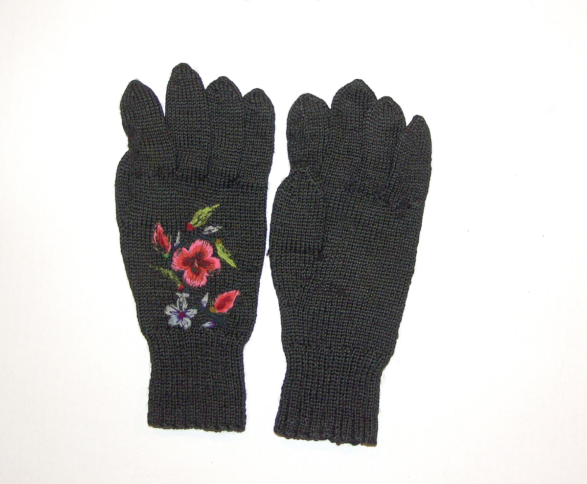1 par svarte strikkede vanter i ull, med broderte blomstermotiv på håndbaken.